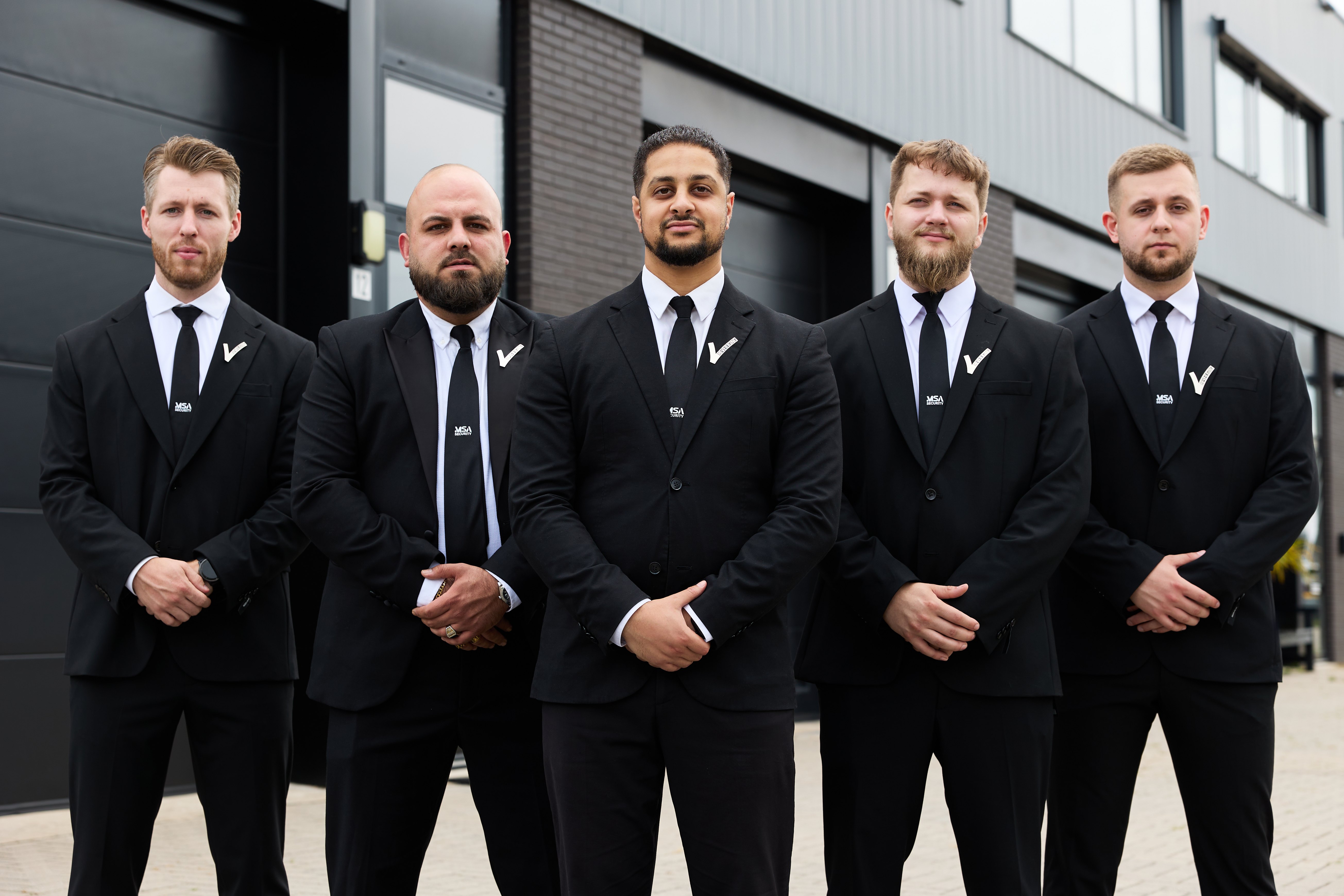 Vijf beveiligers van MSA Security in pak voor een bedrijfspand